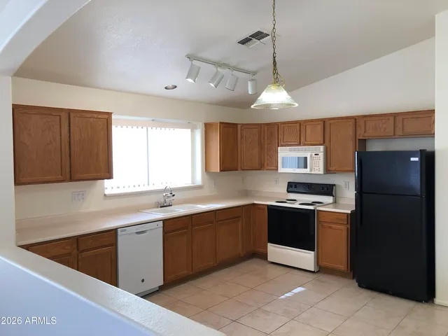 a kitchen with stainless steel appliances granite countertop a sink a stove a refrigerator cabinets and a window