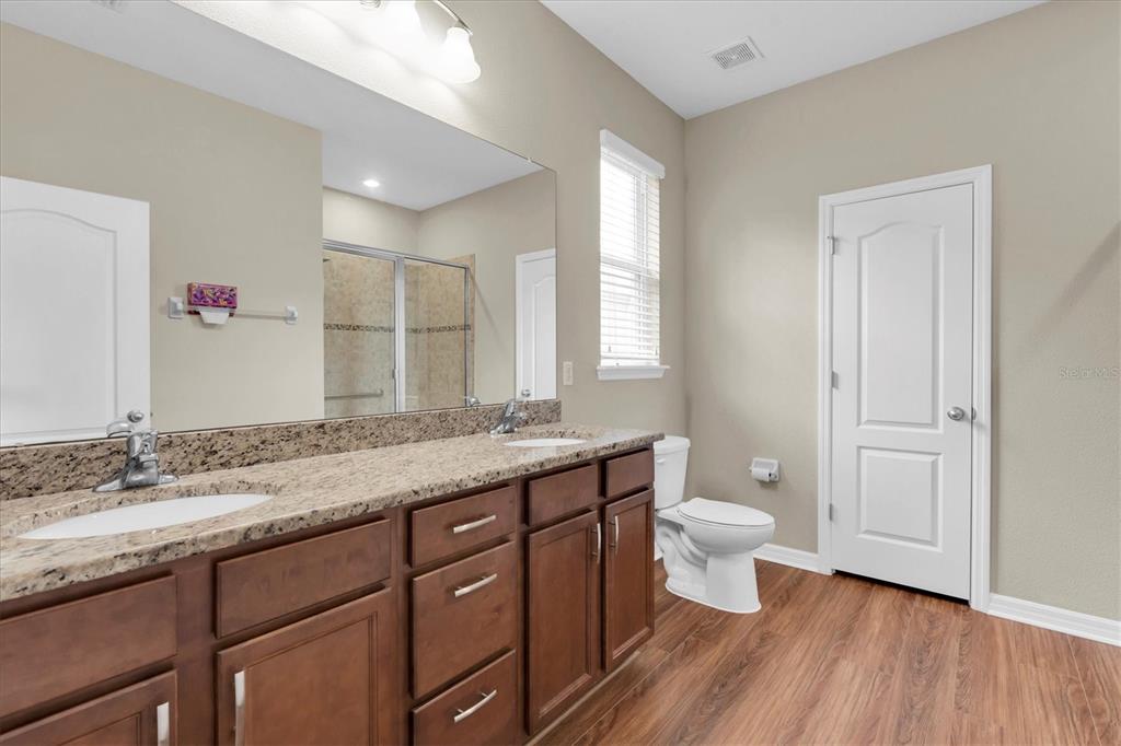 11236 Merganser Way New Port Richey, FL 34654 - Photo 11 of 41 a bathroom with a granite countertop sink a toilet and a large mirror