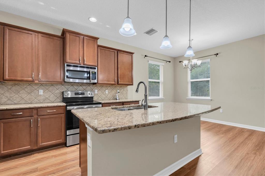 11236 Merganser Way New Port Richey, FL 34654 - Photo 6 of 41 a kitchen with kitchen island granite countertop a sink cabinets and wooden floor