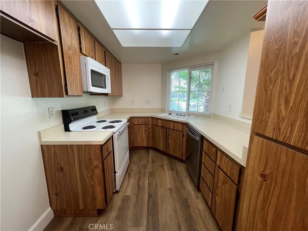 12555 Euclid Street, Unit 21 Garden Grove, CA 92843 - Photo 3 of 7 a kitchen with stainless steel appliances granite countertop a stove a sink dishwasher and a refrigerator with wooden floor