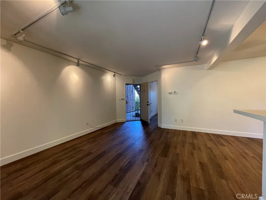 12555 Euclid Street, Unit 21 Garden Grove, CA 92843 - Photo 4 of 7 an empty room with wooden floor and windows
