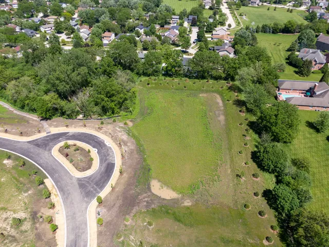 an aerial view of residential houses with outdoor space and trees