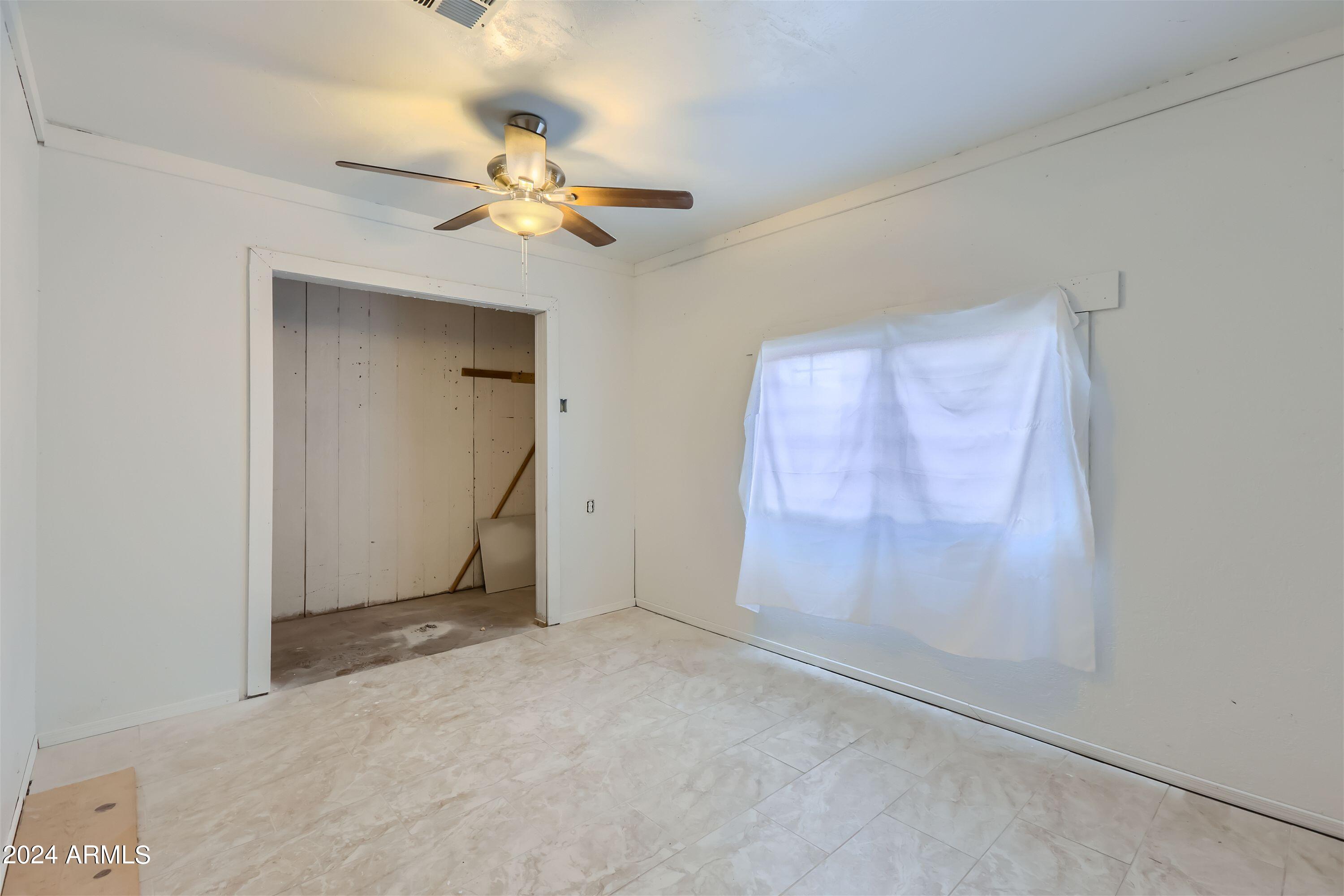 5202 West Berkeley Road Phoenix, AZ 85035 - Photo 11 of 12 an empty room with a ceiling fan and a window
