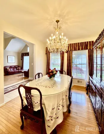 a dining room with wooden floor a chandelier a wooden table and chairs