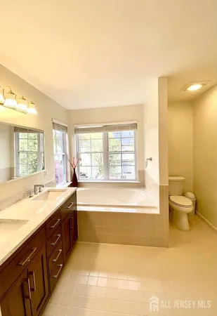 a spacious bathroom with a tub sink and mirror