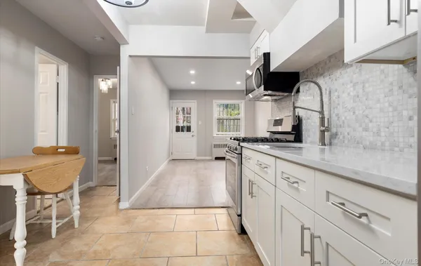 a large kitchen with granite countertop lots of white cabinets and a sink