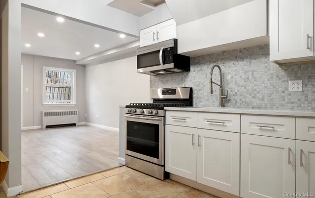 a kitchen with granite countertop a sink stainless steel appliances and white cabinets