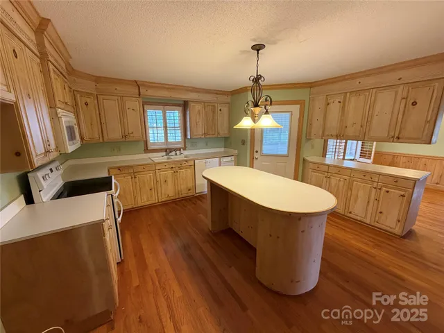 a large kitchen with kitchen island wooden floors white walls appliances and cabinets