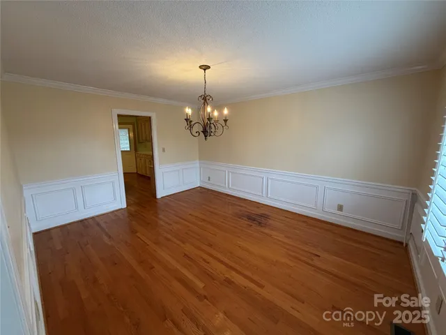 a view of a room with wooden floor and chandelier