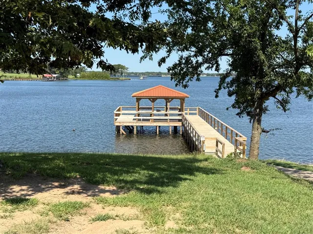 a view of pool with lawn chairs and large trees