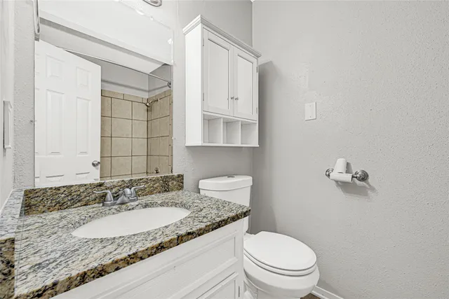 a bathroom with a granite countertop sink a toilet and a mirror