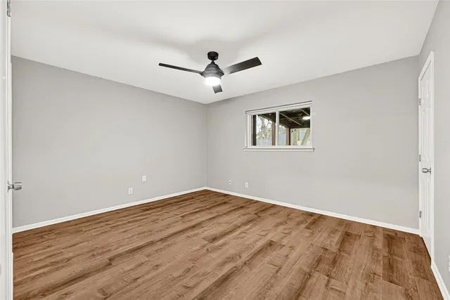 a view of empty room with wooden floor and ceiling fan