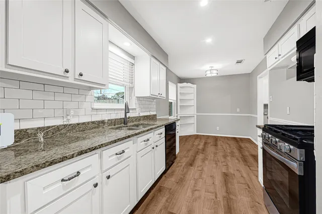 a kitchen with granite countertop a sink wooden floor and stainless steel appliances