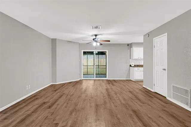 a view of empty room with wooden floor and fan