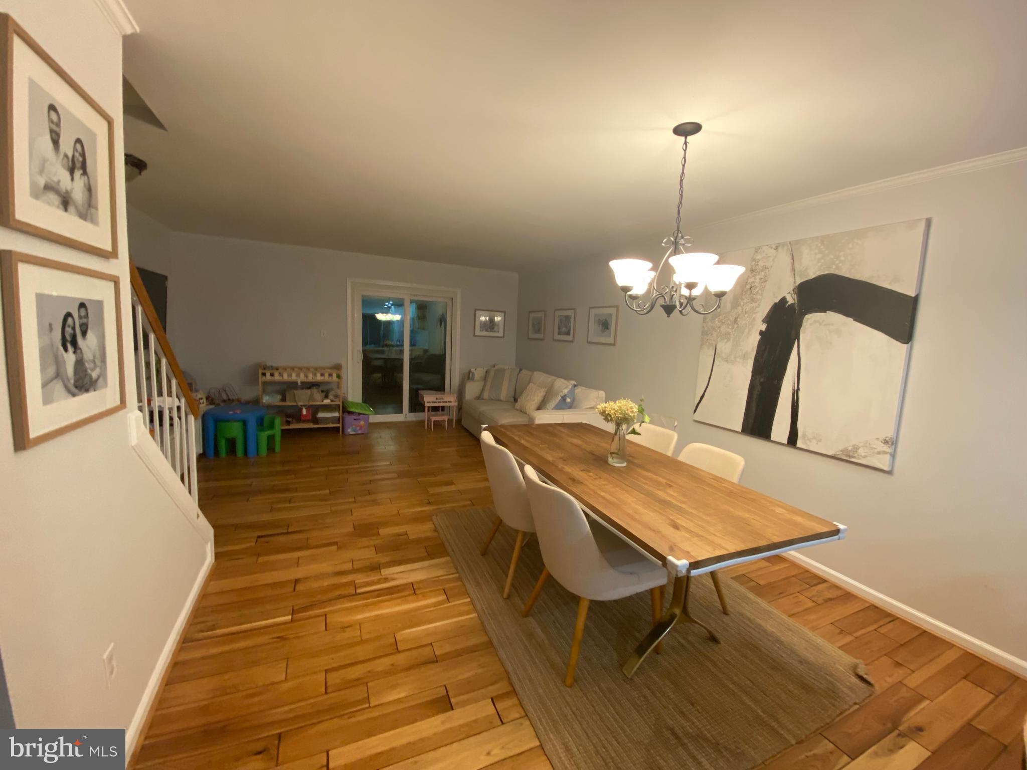 8523 Gambel Oak Drive Springfield, VA 22153 - Photo 36 of 41 a dining room with wooden floor a chandelier a wooden table and chairs
