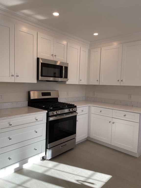 55 Dalton Road, Unit 1 Belmont, MA 02478 - Photo 11 of 16 a kitchen with granite countertop white cabinets and stainless steel appliances