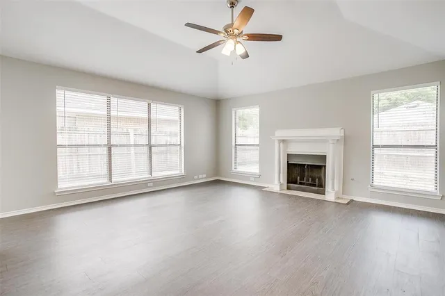 an empty room with windows fireplace and a wooden floor