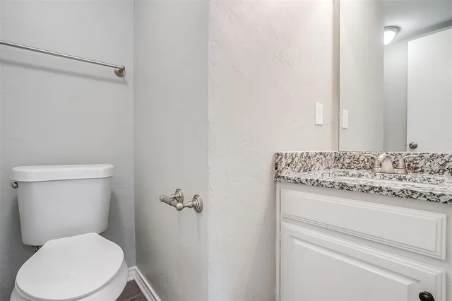 a bathroom with a granite countertop toilet and a sink