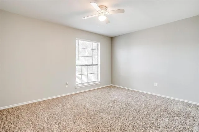 an empty room with chandelier fan and windows