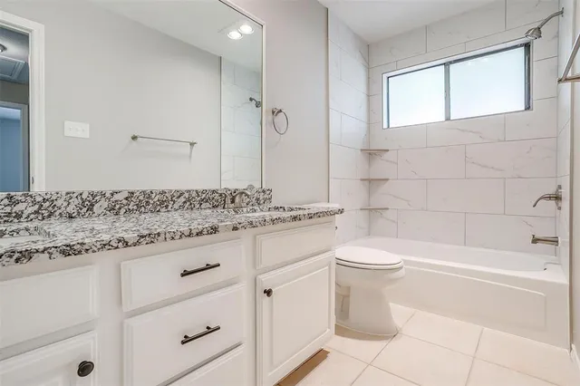 a bathroom with a granite countertop sink a toilet and bathtub