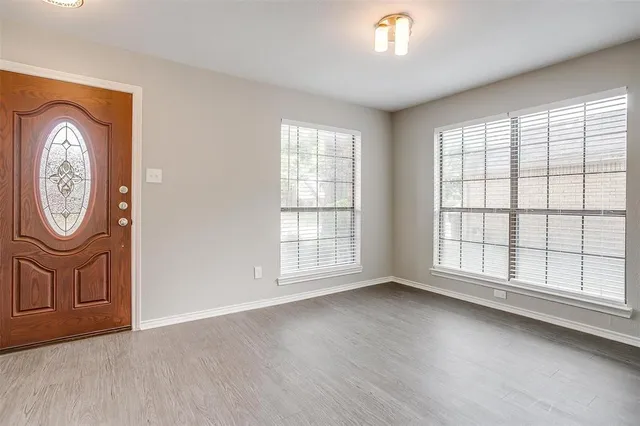 a view of an empty room with a window and wooden floor