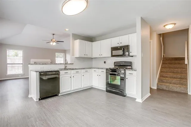 a kitchen with granite countertop white cabinets and stainless steel appliances
