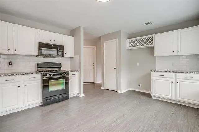 a kitchen with granite countertop white cabinets and stainless steel appliances