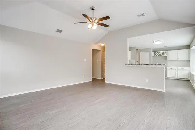 an empty room with wooden floor and a ceiling fan