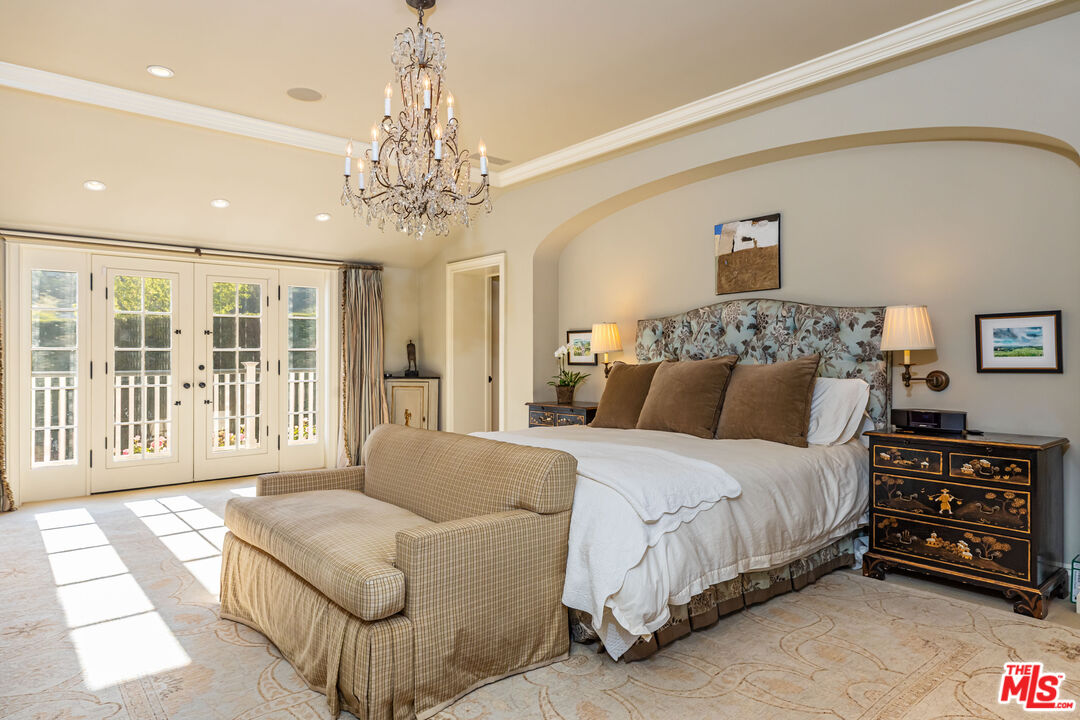 685 Elkins Road Los Angeles, CA 90049 - Photo 12 of 24 a spacious bedroom with a bed and a chandelier