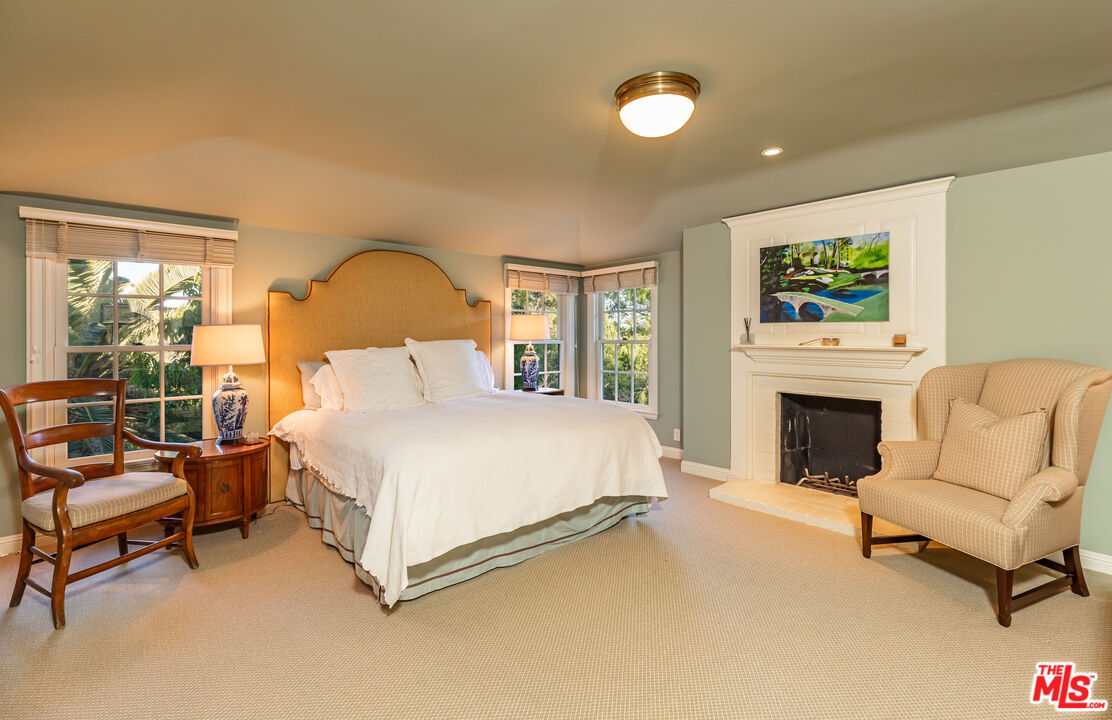685 Elkins Road Los Angeles, CA 90049 - Photo 16 of 24 a spacious bedroom with a bed and a fireplace