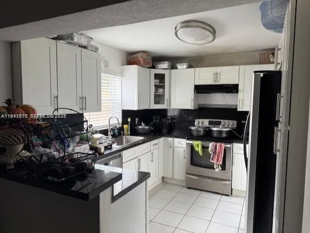 a kitchen with a sink appliances cabinets and furniture