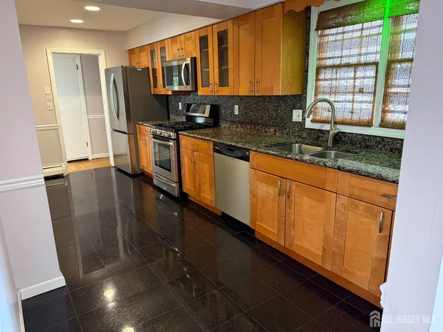 a kitchen with stainless steel appliances a sink a refrigerator and a granite counter tops