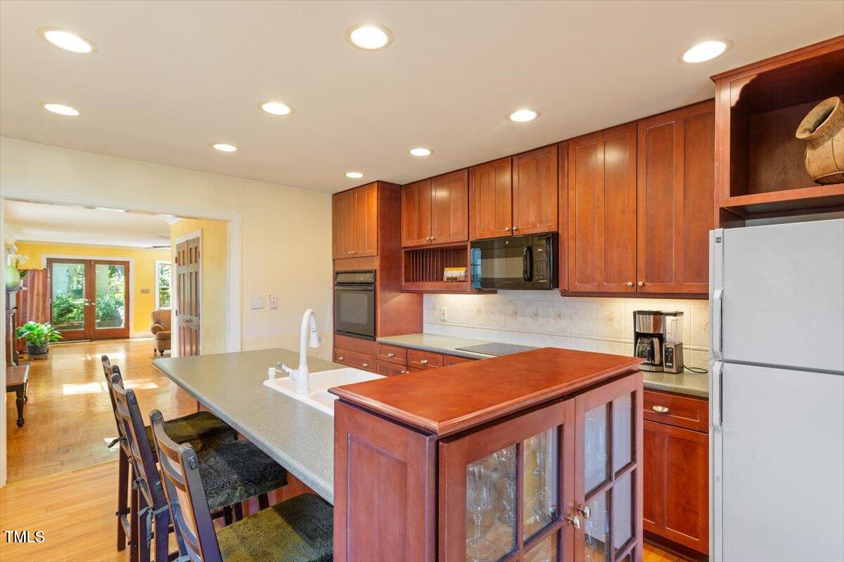 708 Mills Street Raleigh, NC 27608 - Photo 18 of 39 a kitchen with stainless steel appliances granite countertop a sink a refrigerator and wooden cabinets
