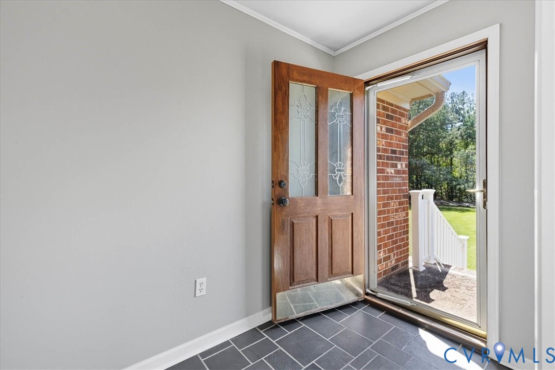 Entrance foyer featuring crown molding and dark ti