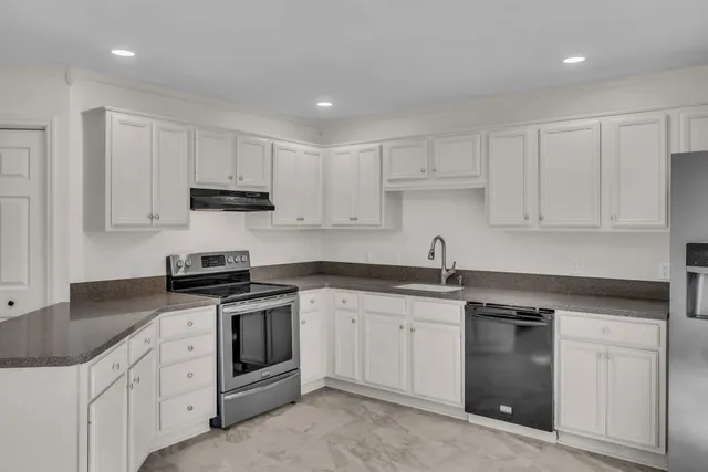 a kitchen with white cabinets stainless steel appliances and sink