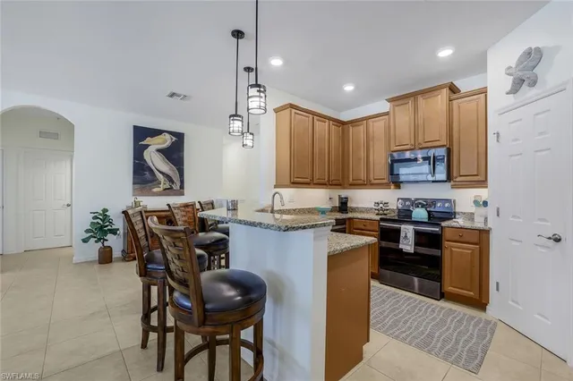 a kitchen with kitchen island granite countertop wooden cabinets a stove a microwave a island with a dining table and chairs