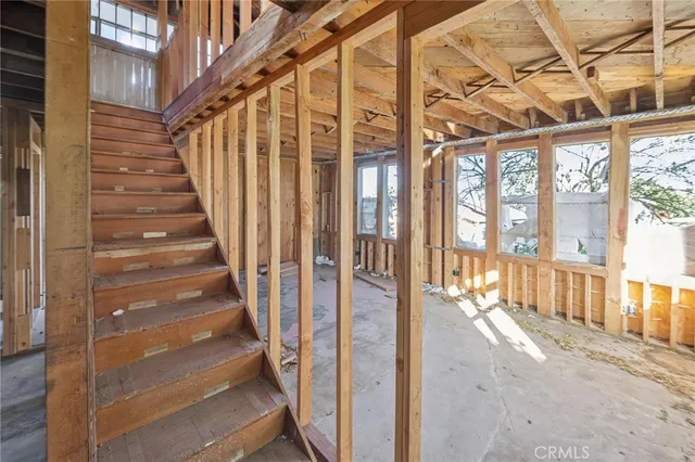 a view of an empty room with wooden floor and stairs