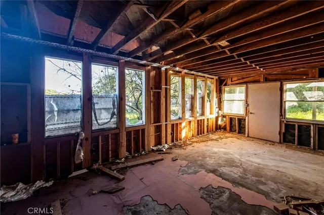 a view of an empty room with wooden floor and windows