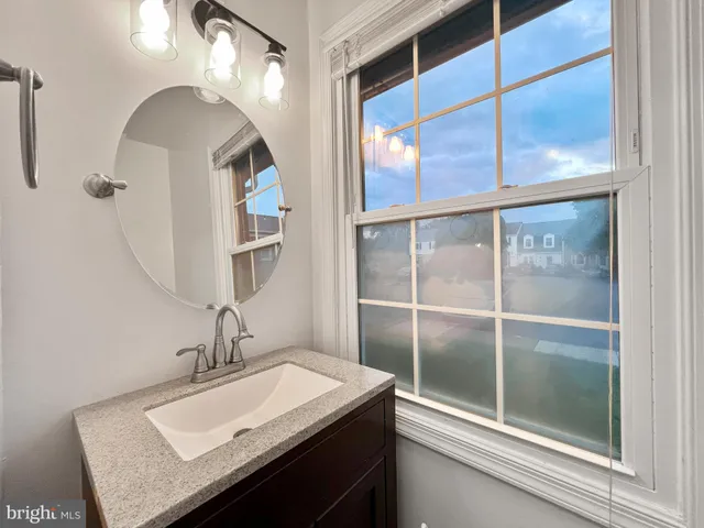 a bathroom with a sink and mirror with bathtub