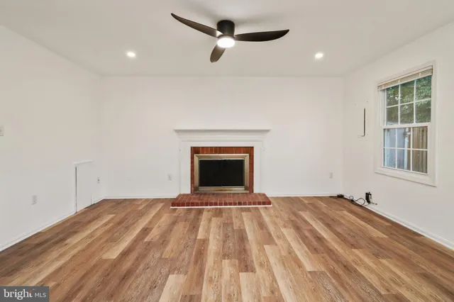a view of empty room with a fireplace and wooden floor