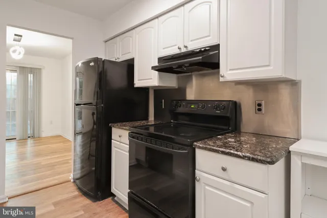 a kitchen with granite countertop white cabinets and stainless steel appliances