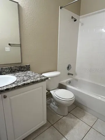 a bathroom with a granite countertop toilet a sink and a bathtub