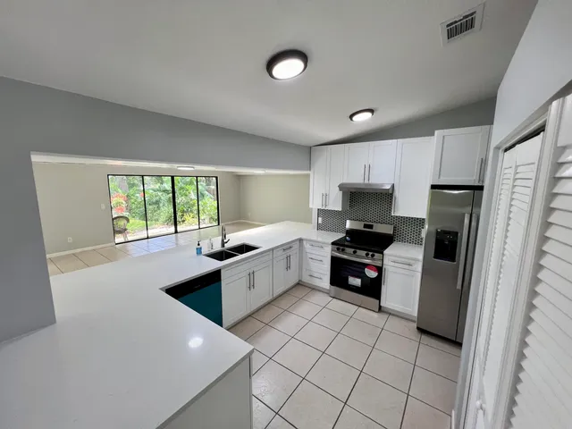 a large kitchen with a stove a refrigerator and a sink