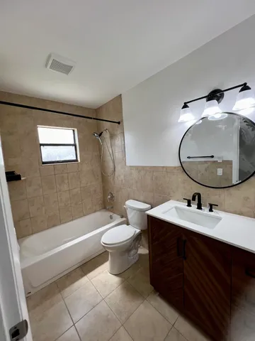 a bathroom with a sink vanity mirror bathtub and toilet