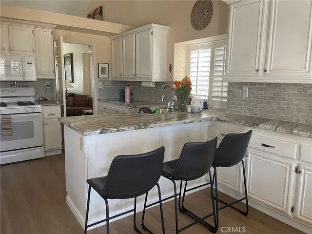 a kitchen with stainless steel appliances granite countertop a stove a sink a microwave a refrigerator and white cabinets