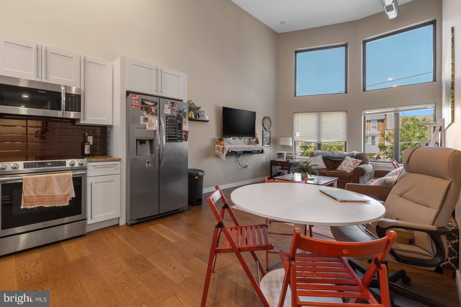 1142 Crease Street, Unit 2L Philadelphia, PA 19125 - Photo 2 of 17 a kitchen with stainless steel appliances a dining table chairs stove refrigerator and microwave