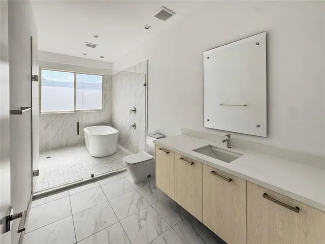 a large white kitchen with a sink stainless steel appliances and cabinets