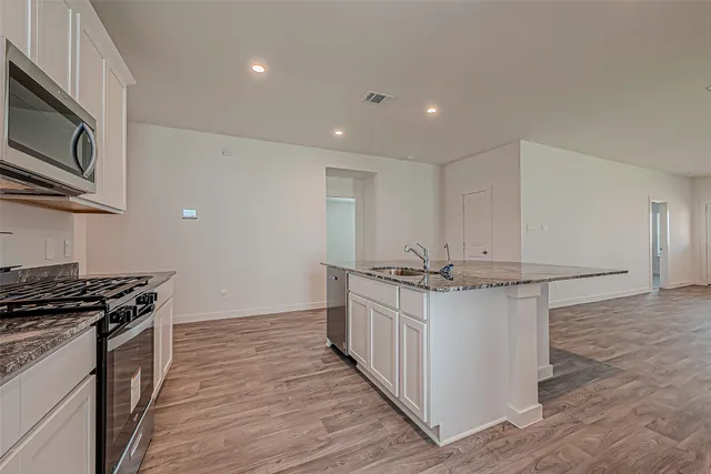 a kitchen with stainless steel appliances a stove top oven a sink and a refrigerator