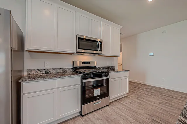 a kitchen with stainless steel appliances granite countertop a stove and a microwave