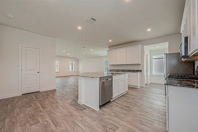 a kitchen with granite countertop a stove top oven and cabinets